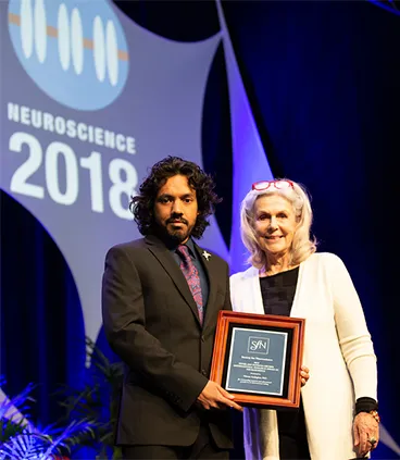 Photograph of Vikram Gadagkar receiving the Gruber Award from Patricia Gruber